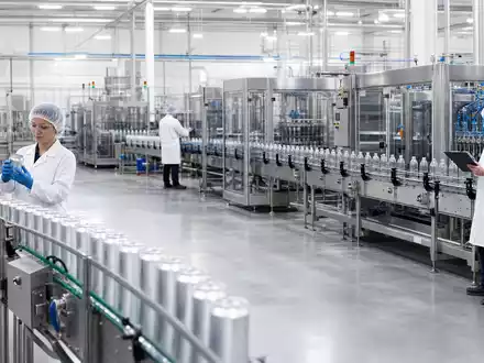 Fotorealistische Abfüllanlage zeigt Keurig Dr Pepper (ISIN US49271V1008) bei moderner Getränkeproduktion mit Edelstahl-Fließbändern und Mitarbeitern - Foto: THN