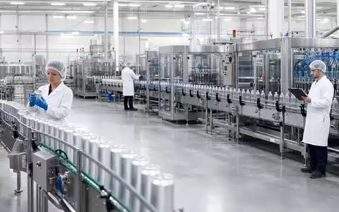 Fotorealistische Abfüllanlage zeigt Keurig Dr Pepper (ISIN US49271V1008) bei moderner Getränkeproduktion mit Edelstahl-Fließbändern und Mitarbeitern - Foto: THN