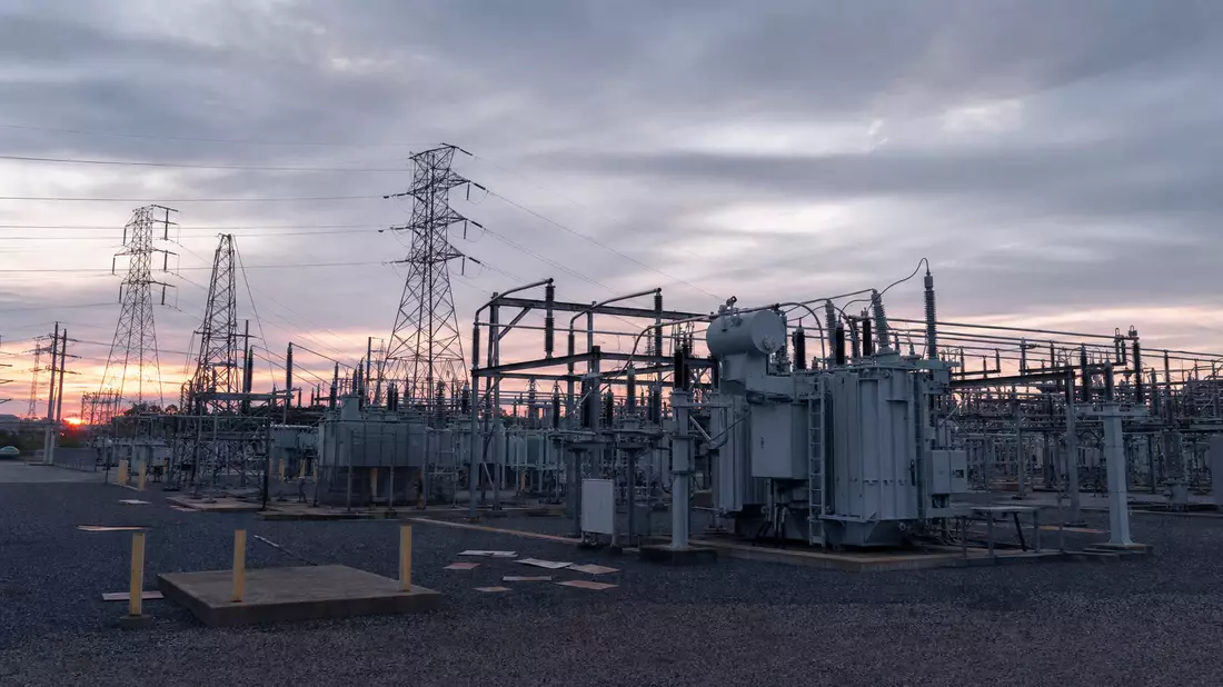 Umspannwerk mit Transformatoren und Hochspannungsmasten bei Dämmerung in New Jersey