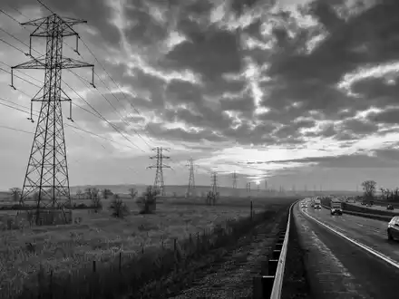 SchwarzweiĂ-Reportagefoto zeigt Public Service Ent. Aktie US7445731067 nahe Hochspannungsmasten entlang eines Highways heute - Foto: THN