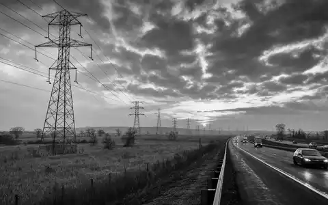 Schwarzweiß-Reportagefoto zeigt Public Service Ent. Aktie US7445731067 nahe Hochspannungsmasten entlang eines Highways heute - Foto: THN