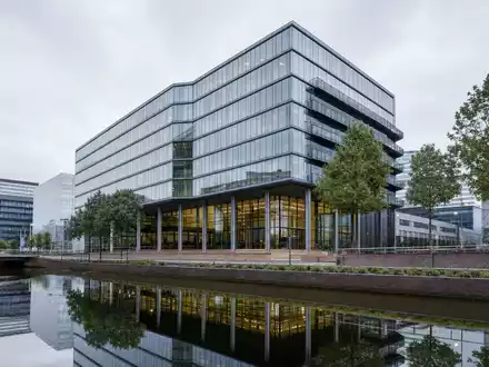 Fotorealistisches Amsterdamer Bürogebäude symbolisiert Prosus N.V., ISIN NL0013654783, moderne Beteiligungsholding am Kanal - Foto: THN