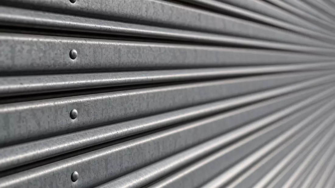 Makrofoto der Metallstruktur eines grauen Rolltors mit Nieten