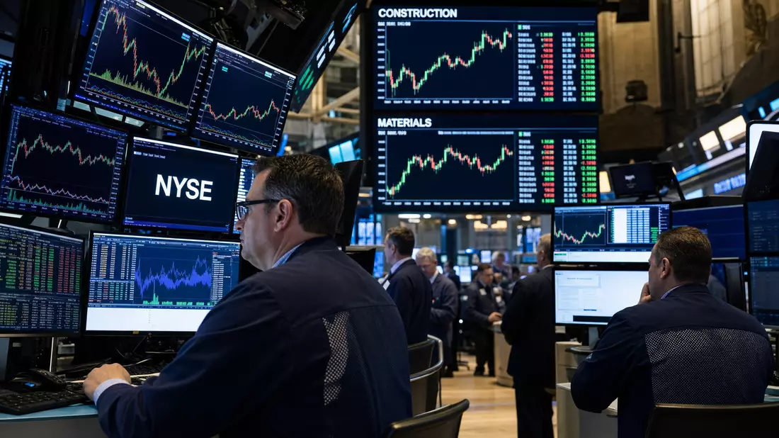 NYSE-Handelssaal mit Händlern vor Bildschirmen und Baustoffsektor-Kurscharts
