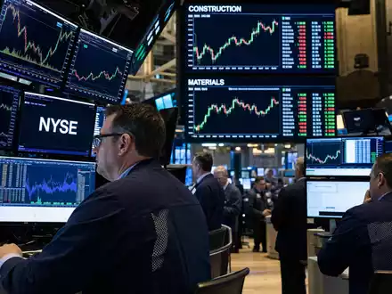 Vulcan Materials US9291601097 zeigt NYSE Handelssaal mit Händlern vor Bildschirmen und Baustoffsektor-Charts im Hintergrund - Foto: THN