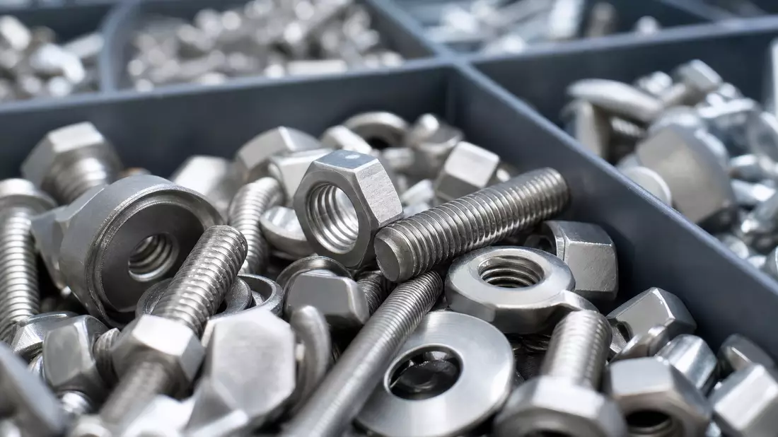 Extreme Nahaufnahme von Metallschrauben, Muttern und Unterlegscheiben in einer Box