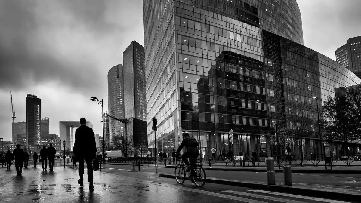 Schwarzweiß-Straßenszene mit Bürotürmen, Fußgängern und Radfahrer im Pariser Geschäftsviertel