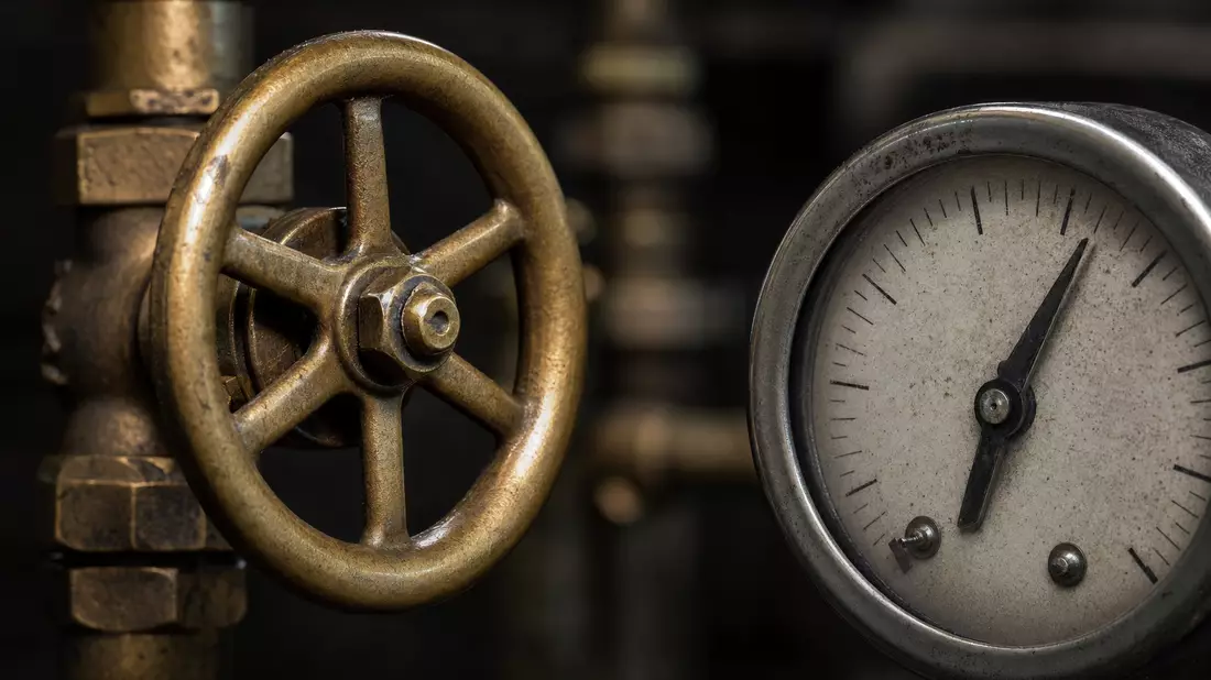 Makroaufnahme eines Messing-Ventilrads und eines analogen Zählwerk-Manometers