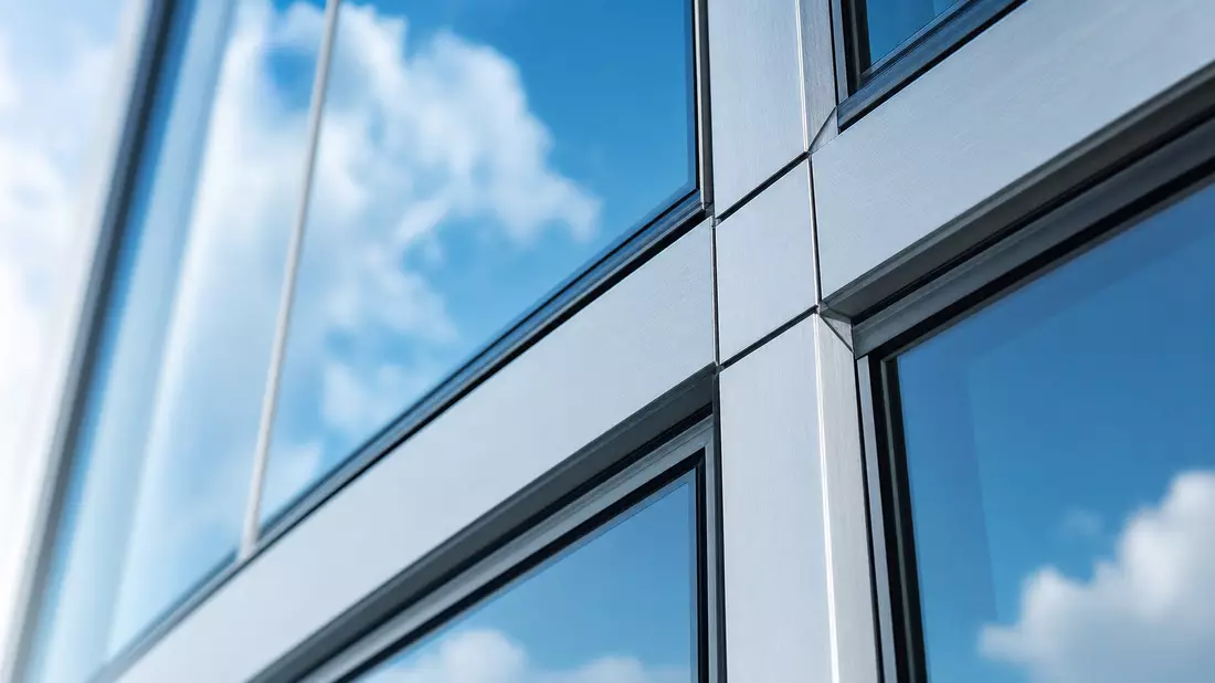 Makrofoto einer Glasfassade mit Aluminiumrahmen und Lichtreflexionen