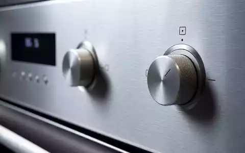 Electrolux AB (ISIN SE0016589188) zeigt eine Makroaufnahme von gebürstetem Edelstahl und präzisen Steuerknöpfen eines Haushaltsgeräts - Foto: THN