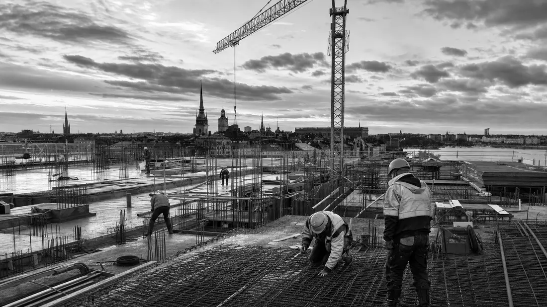 Schwarzweiß-Reportagefoto einer Baustelle mit Kran vor Stockholmer Skyline