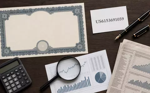 Flatlay-Arrangement mit Aktienzertifikat und ISIN-Karte illustriert Moody's Corporation, ISIN US6153691059, im Bereich Finanzdienstleistungen - Foto: THN