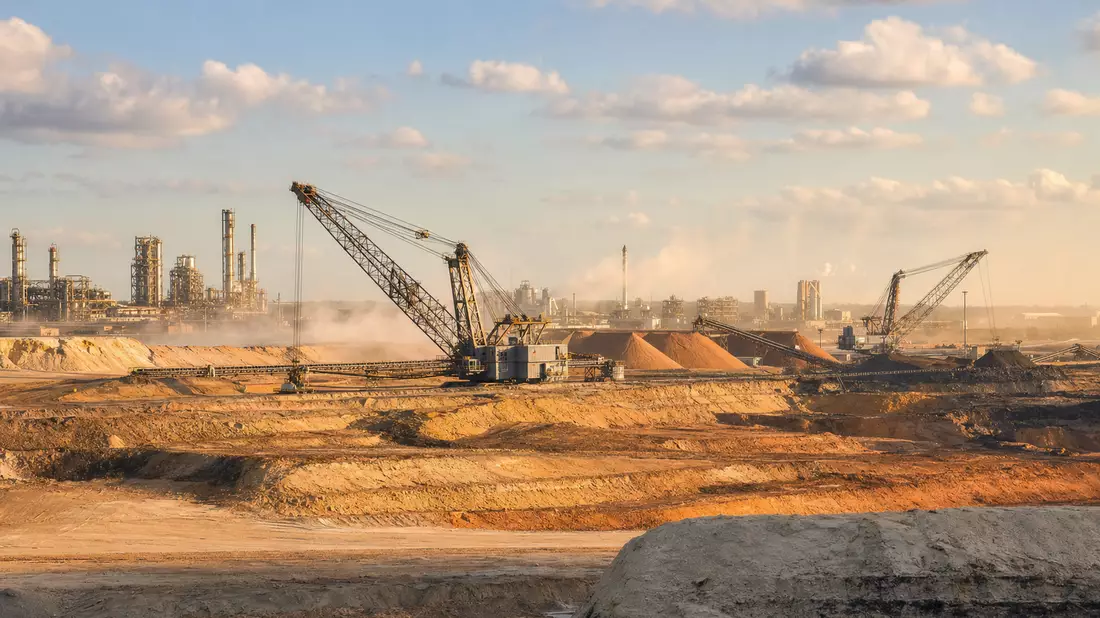 Fotorealistische Tagebau-Fördermine mit Baggern und Mineralhalden bei warmem Abendlicht