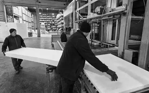 Schwarzweiß-Reportage aus Dämmstofffabrik illustriert Kingspan Group plc, ISIN IE0004927939, dokumentarisch mit Arbeitern und Materiallager - Foto: THN