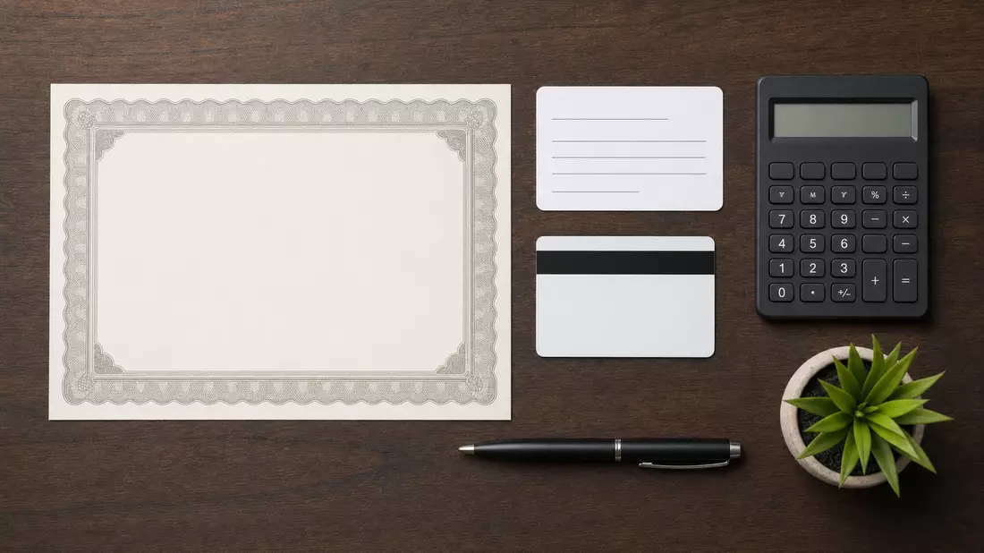 Flatlay mit Aktienzertifikat, ISIN-Karte, Bankkarte, Taschenrechner und Stift