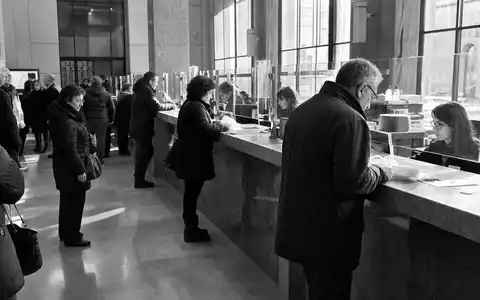 Schwarzweiß-Reportage einer italienischen Bankfiliale zeigt Alltag im Bankwesen, passend zu UniCredit S.p.A., ISIN IT0004781412, Mailand - Foto: THN