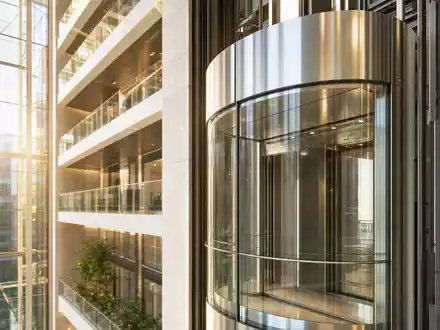 Otis Worldwide Corp. (US68902V1070): moderner Glasaufzug im lichtdurchfluteten Hochhaus-Atrium, realistische hochwertige Architekturfotografie eines Wolkenkratzers - Foto: THN