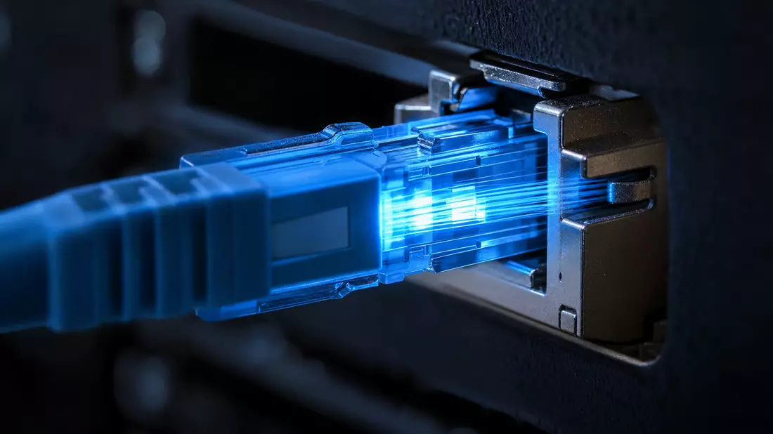 Makroaufnahme eines Glasfaser-Netzwerkports mit blau leuchtendem Licht