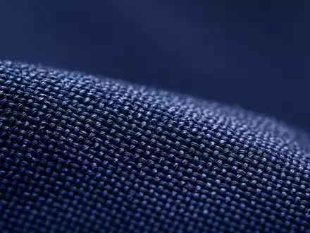 Cintas Corp. US1729081035 Makro-Detailaufnahme der Gewebetextur eines marineblauen Berufsuniforms unter präzisen Ringleuchten - Foto: THN