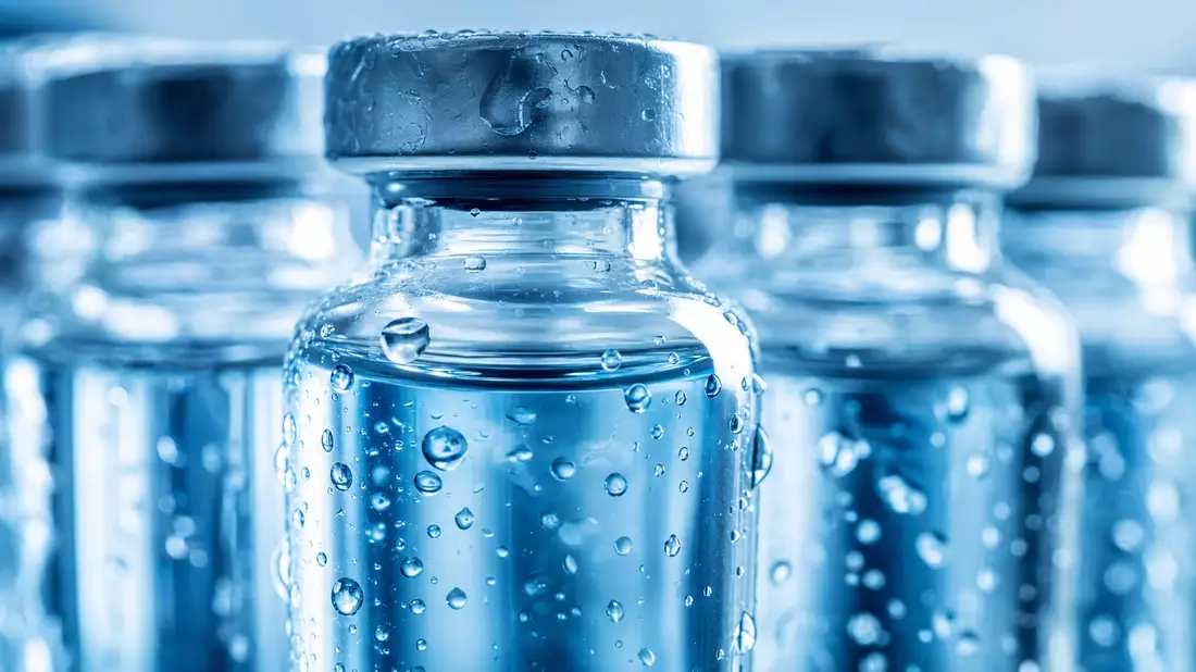 Makrofoto von beschlagenen Glasfläschchen mit blauer Flüssigkeit in Nahaufnahme