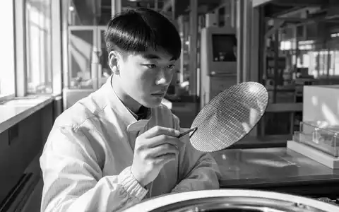 Texas Instruments (US8825081040) dokumentiert in Schwarzweiß einen Ingenieur, der einen Silizium-Wafer in der Fabrikhalle begutachtet - Foto: THN