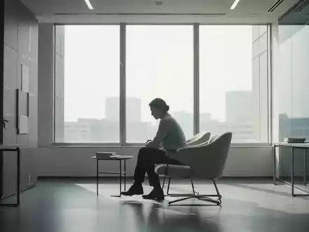 Eine Person sitzt nachdenklich in einem ruhigen, modernen Büroraum, mit sanftem Licht, das durch ein großes Fenster fällt. - Foto: über boerse-global.de