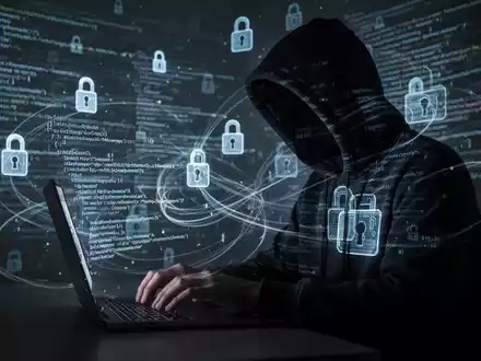 Verschattete Gestalt in dunklem Hoodie tippt auf Laptop, umgeben von digitalen Schlosssymbolen und Code. - Foto: über boerse-global.de