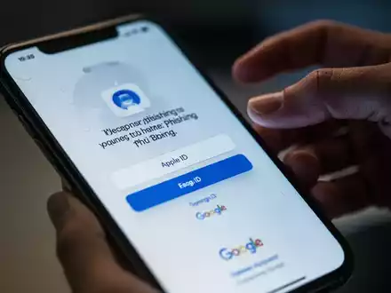Nahaufnahme eines Smartphone-Bildschirms mit einer Phishing-Nachricht und einer verschwommenen Hand, die nach dem Telefon greift. - Foto: über boerse-global.de
