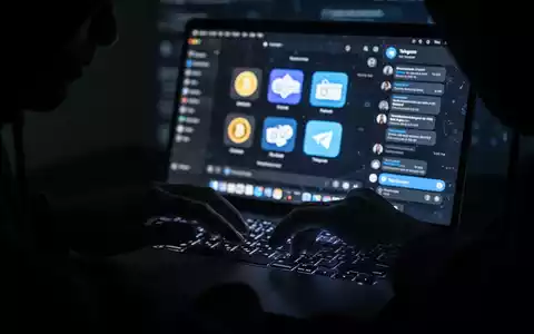 Nahaufnahme von Händen, die auf einer Laptop-Tastatur tippen, mit digitalen Kryptowährungs- und Telegram-Symbolen auf dem Bildschirm, die Cyberdiebstahl symbolisieren. - Foto: über boerse-global.de