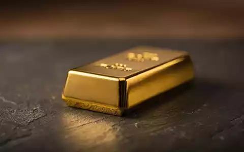 Ein glänzender Goldbarren liegt auf einer dunklen Oberfläche, umgeben von gedämpften Farbtönen. - Foto: über boerse-global.de