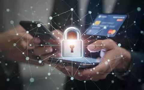 Digitales Vorhängeschloss-Symbol über einem Netzwerk, mit unscharfen Händen, die ein Smartphone für Online-Banking nutzen. Betont Sicherheit. - Foto: über boerse-global.de