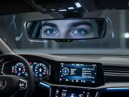 Nahaufnahme der Augen eines Autofahrers im Rückspiegel, mit subtilen Infrarotlichtern, die die Überwachung durch ein Fahrerassistenzsystem andeuten. - Foto: über boerse-global.de