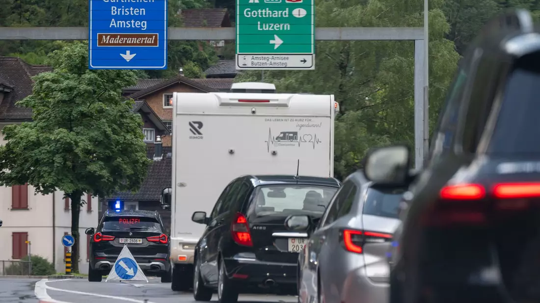 Die Polizei leitet ausweichende Autos in Amsteg wieder auf die Autobahn. - Bild: Urs Flueeler/KEYSTONE/dpa