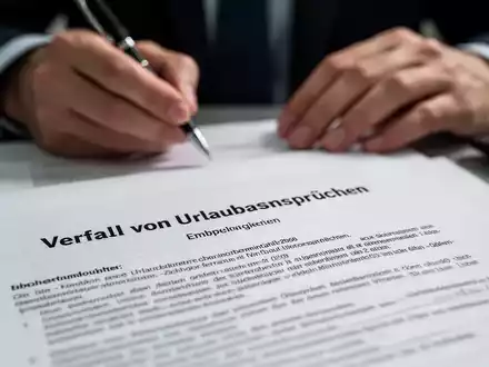 Ein Detailbild eines juristischen Dokuments mit verschwommenen Händen, die einen Stift halten, symbolisiert Arbeitsrecht und Urlaubsansprüche. - Foto: über boerse-global.de