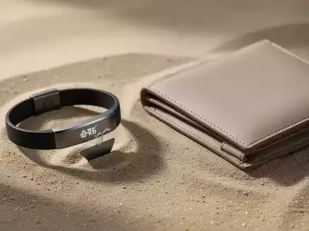 Minimalistische Alltagsaccessoires wie ein NFC-Armband und eine sandfarbene Geldbörse auf einer strukturierten Oberfläche. - Foto: über boerse-global.de