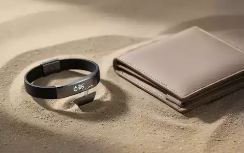 Minimalistische Alltagsaccessoires wie ein NFC-Armband und eine sandfarbene Geldbörse auf einer strukturierten Oberfläche. - Foto: über boerse-global.de