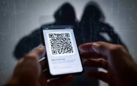 Nahaufnahme eines Smartphones, das einen bösartigen QR-Code anzeigt, mit verschwommenen HĂ€nden im Vordergrund. - Foto: ĂŒber boerse-global.de