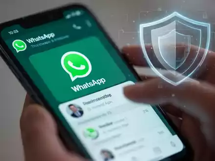 Ein Smartphone zeigt die WhatsApp-Benutzeroberfläche, während Hände damit interagieren, mit einem digitalen Schutzschild im Hintergrund. - Foto: über boerse-global.de