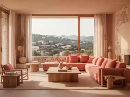 Ein warm minimalistisch eingerichtetes Wohnzimmer mit natürlichen Materialien, Sonnenlicht und Blick auf eine mediterrane Landschaft. - Foto: über boerse-global.de