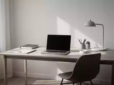Ein minimalistisches Heimbüro mit einem einzigen Schreibtisch, Laptop und wenigen Gegenständen, symbolisiert Klarheit und Organisation. - Foto: über boerse-global.de
