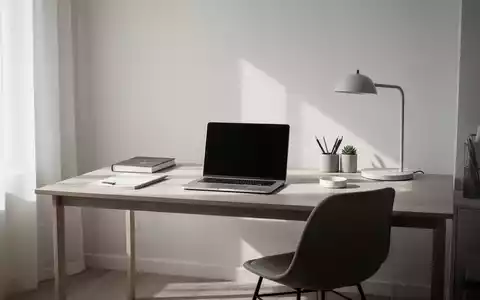 Ein minimalistisches Heimbüro mit einem einzigen Schreibtisch, Laptop und wenigen Gegenständen, symbolisiert Klarheit und Organisation. - Foto: über boerse-global.de