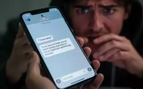 Nahaufnahme eines Smartphone-Bildschirms mit verdächtiger Textnachricht, gehalten von einer Person mit besorgtem Gesichtsausdruck im unscharfen Hintergrund. Fokus auf digitalen Betrug und Spam-Nachrichten. - Foto: über boerse-global.de