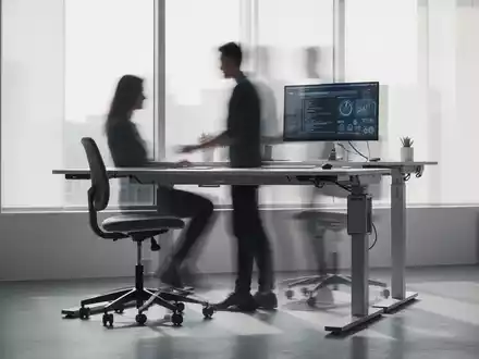 Ein moderner Arbeitsplatz mit höhenverstellbarem Schreibtisch und ergonomischem Rollhocker, der flexible Sitzmöglichkeiten symbolisiert. - Foto: über boerse-global.de
