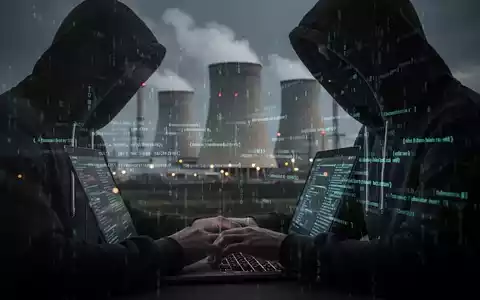 Eine Person im Hoodie tippt auf einem Laptop, im Hintergrund ein Atomkraftwerk. Symbolisiert einen Cyberangriff auf kritische Infrastruktur. - Foto: ĂŒber boerse-global.de