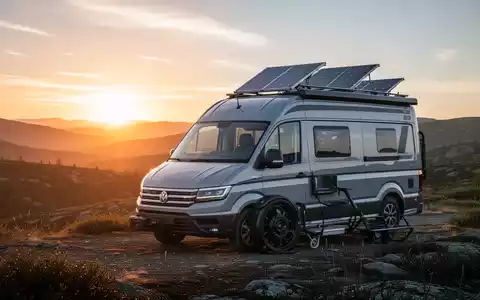 Ein moderner Camper Van, geparkt in einer malerischen Naturlandschaft bei Sonnenaufgang, mit sichtbaren Solarpaneelen auf dem Dach. - Foto: über boerse-global.de