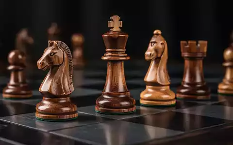 Nahaufnahme von eleganten Holzschachfiguren auf einem dunklen Schachbrett, die Intelligenz und Strategie symbolisieren. - Foto: über boerse-global.de