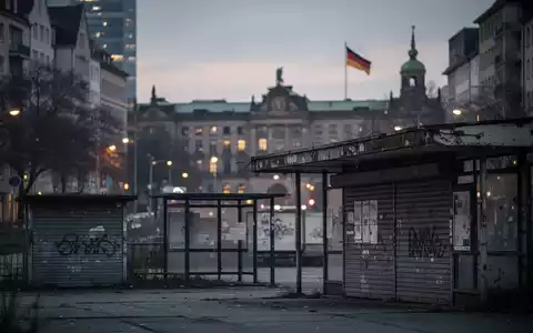 Eine abendliche Stadtlandschaft mit verschwommenen Gebäuden und Anzeichen alternder Infrastruktur, die kommunale Finanznot symbolisiert. - Foto: über boerse-global.de
