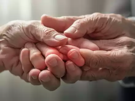 Nahaufnahme einer Hand, die sanft die Fingerknöchel der anderen Hand berührt, was auf Fingergelenkarthrose hindeutet. - Foto: über boerse-global.de