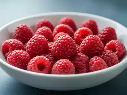 Nahaufnahme von frischen, leuchtend roten Himbeeren, die sorgfältig in einer flachen, weißen Keramikschale angeordnet sind. - Foto: über boerse-global.de