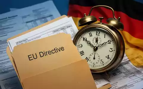 Eine leicht geöffnete Akte mit der Aufschrift 'EU-Richtlinie' und eine Uhr, die eine verstrichene Frist anzeigt, mit deutscher Flagge im Hintergrund. - Foto: über boerse-global.de